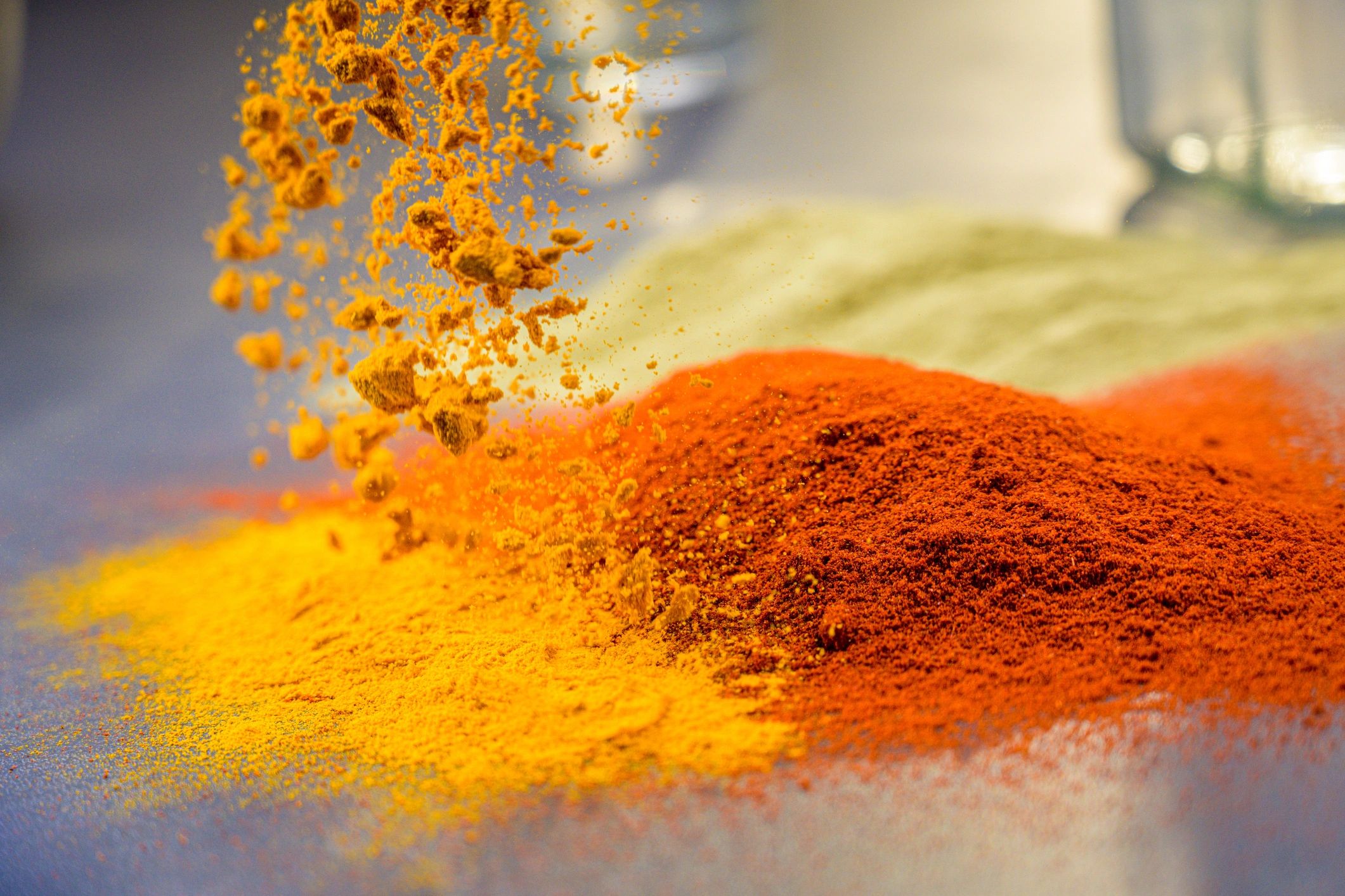 Turmeric powder falling next to red chili powder