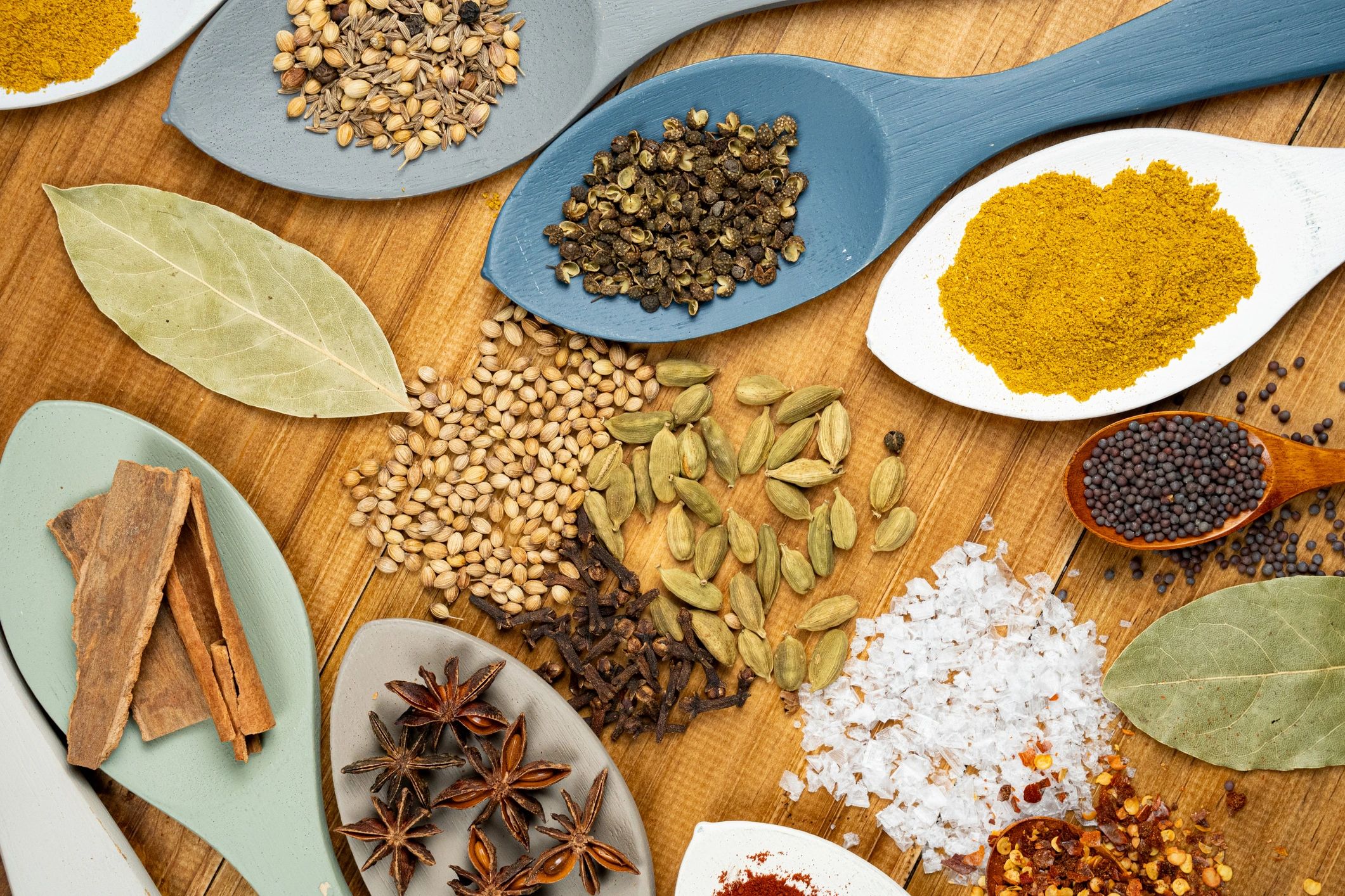 Assorted colorful spices and herbs arranged on a rustic wooden surface